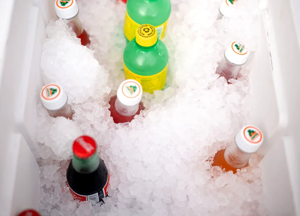 Assorted cold cans and bottles chilling over ice